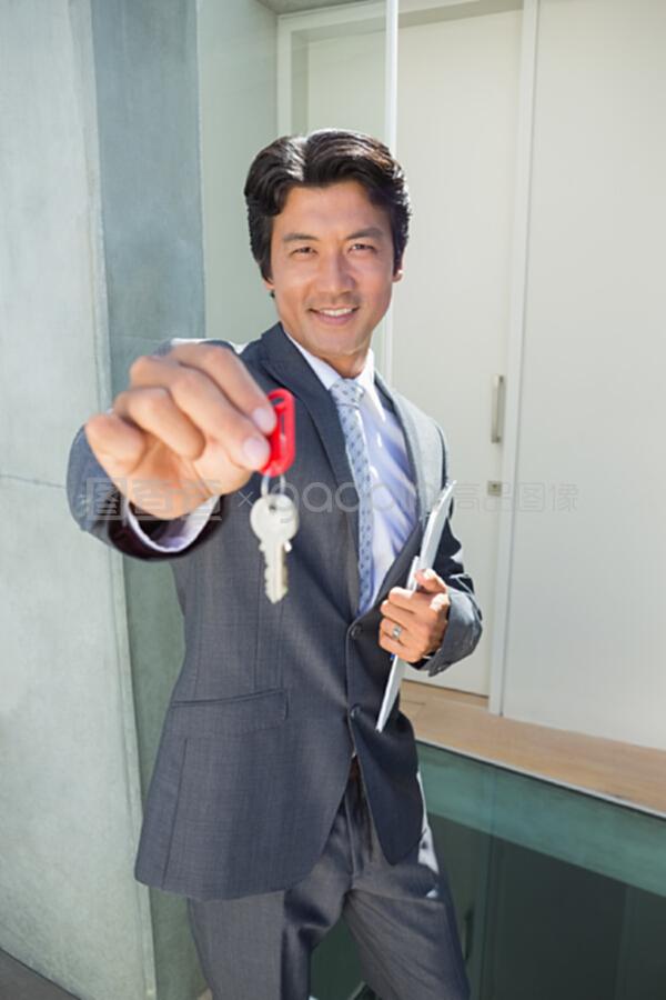 自信的地产代理站在门口,展示钥匙